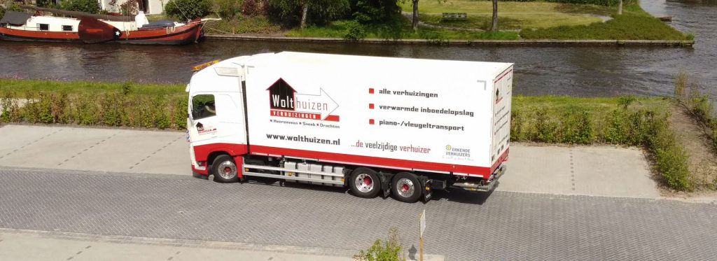 Vrachtwagen van Wolthuizen geparkeerd op terrein bij omliggend water